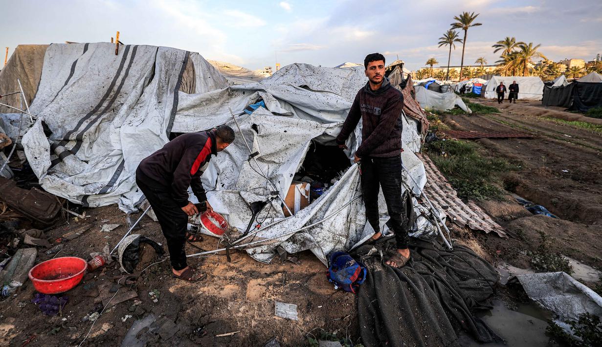 Untuk diketahui, kondisi kemanusiaan di Deir el-Balah terus memburuk, seiring meningkatnya intensitas serangan Israel di wilayah yang sebelumnya dianggap sebagai salah satu tempat perlindungan terakhir bagi pengungsi Palestina di Gaza. Tampak dalam foto, warga memeriksa kerusakan akibat udara Israel menghantam sebuah lokasi dekat tenda-tenda penampungan pengungsi Palestina di Deir el-Balah, Jalur Gaza tengah pada 25 Maret 2026. (Eyad Baba/AFP)