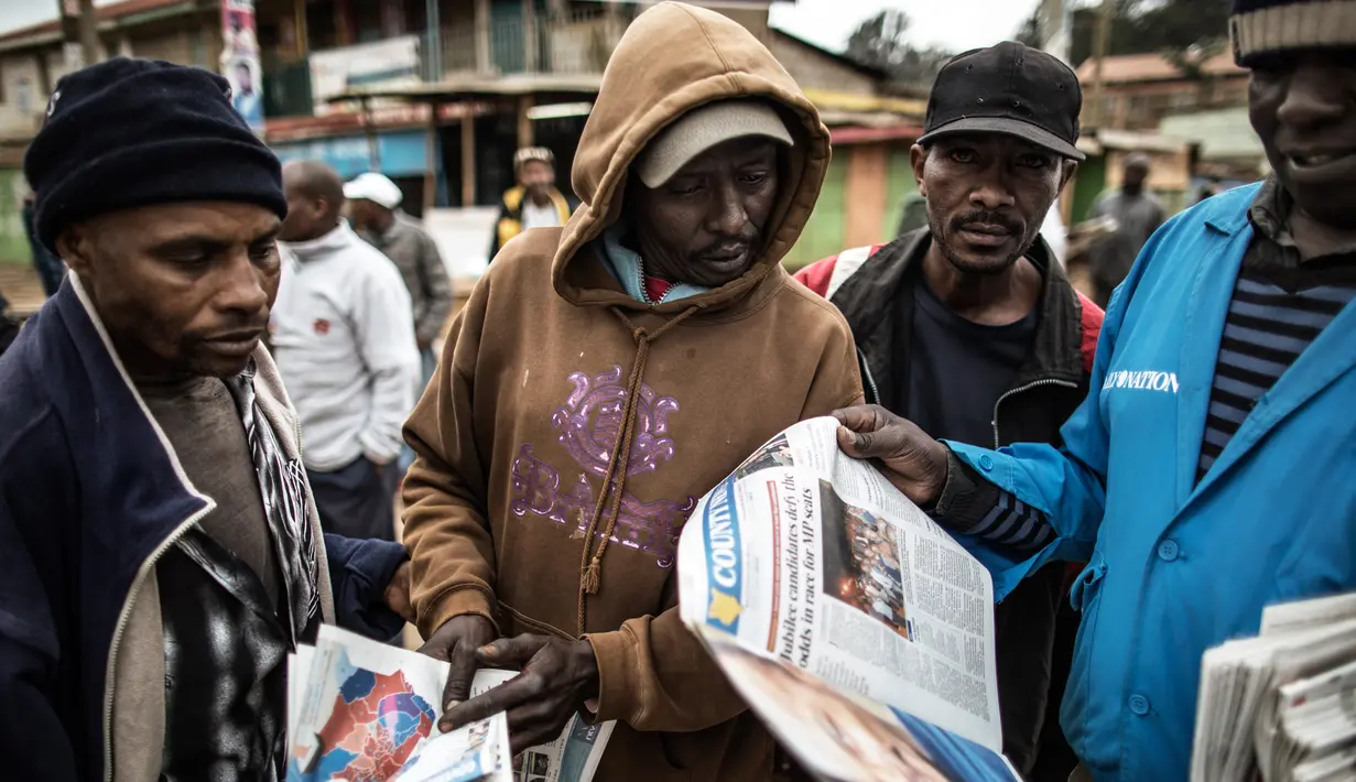 Warga membaca koran di daerah kumuh Kawangare di Nairobi (10/8). Warga Kenya tengah menunggu hasil pemilihan presidennya, antara Uhuru Kenyatta dan pesaingnya, Raila Odinga. (AFP Photo/Marco Longari) 