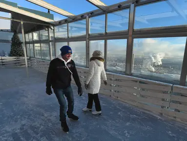 Dua wisatawan tengah menikmati keseruan bermain ice skating di arena ski lantai teratas pusat bisnis Oko Tower di Moskow, Rusia, Kamis (15/12). Arena ski yang berada di ketinggian 354 meter ini diklaim menjadi yang tertinggi di Eropa. (VASILY MAXIMOV/AFP)
