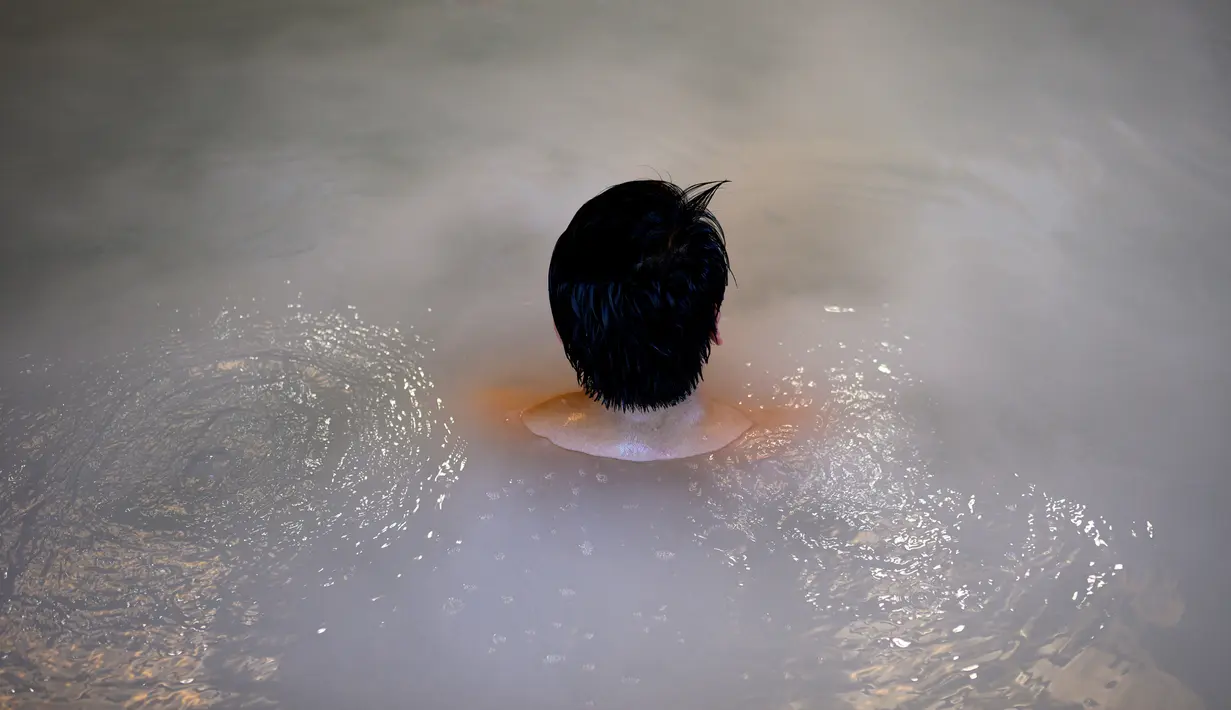 Seorang pria bersantai dalam kolam renang indoor di pemandian air panas Jepang atau onsen di Yokohama, prefektur Kanagawa pada 29 Mei 2020. Dengan pencabutan status darurat nasional pada Senin (25/5) lalu, banyak bisnis yang mulai beroperasi kembali tak terkecuali dengan onsen. (Behrouz MEHRI/AFP)