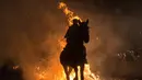 Aksi berkuda menembus kobaran api saat Festival Luminarias, Spanyol, Senin (16/1). Peringatan Hari Santo Antonius dirayakan dengan Festival Luminarias yang unik. (AFP Photo/ PIERRE-PHILIPPE Marcou)