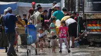 Di kamp Nuseirat, Jalur Gaza Tengah,para pengungsi langsung mengisi wadah mereka ketika bantuan air bersih yang dibawa salah satu truk bantuan tiba. (Eyad BABA/AFP)