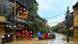 Orang-orang menyusuri jalan yang terendam banjir dengan perahu setelah hujan deras di Hoi An, Vietnam, Kamis 30 Oktober 2025. Sedikitnya sembilan orang tewas dan lima lainnya masih dinyatakan hilang. (NHAC NGUYEN/AFP)