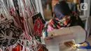 Perajin menyelesaikan pembuatan masker batik di Butik Elemwe, Jakarta, Jumat (2/10/2020). Badan Standardisasi Nasional (BSN) mengeluarkan spesifikasi masker kain ber-SNI yang terbagi menjadi tiga tipe berdasarkan penggunaannya. (Liputan6.com/Faizal Fanani)