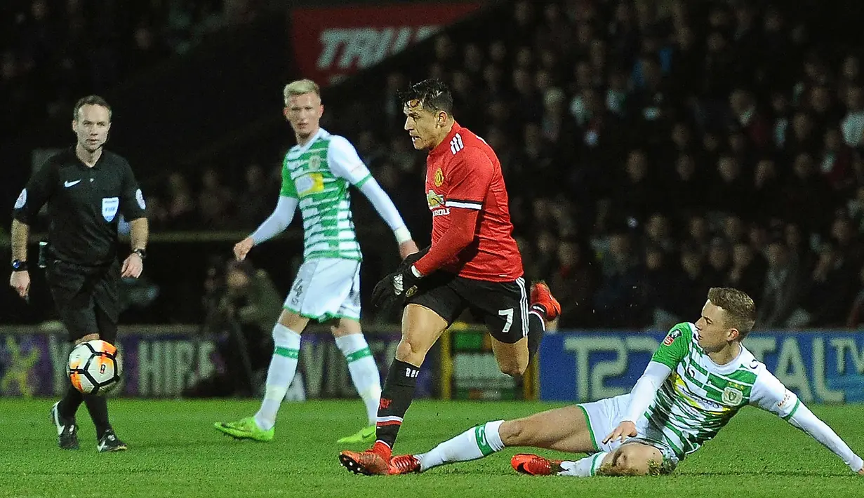 Penyerang MU, Alexis Sanchez berusaha membawa bola dari kawalan gelandang Yeovil Town, Jared Bird pada Piala FA di Huish Park di Yeovil, Somerset (26/1). Sanchez punya kontribusi dalam terciptanya dua gol pertama MU ke gawang Yeovil. (AFP Photo)