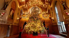 Dekorator menghias pohon cemara besar dari Windsor Great Park di ujung aula St. George di Windsor Castle, Inggris, 30 November 2018. Pohon setinggi 6 meter itu dihias dengan pernak-pernik Natal berwarna emas serta ornamen kerajaan.  (AP/Frank Augstein)