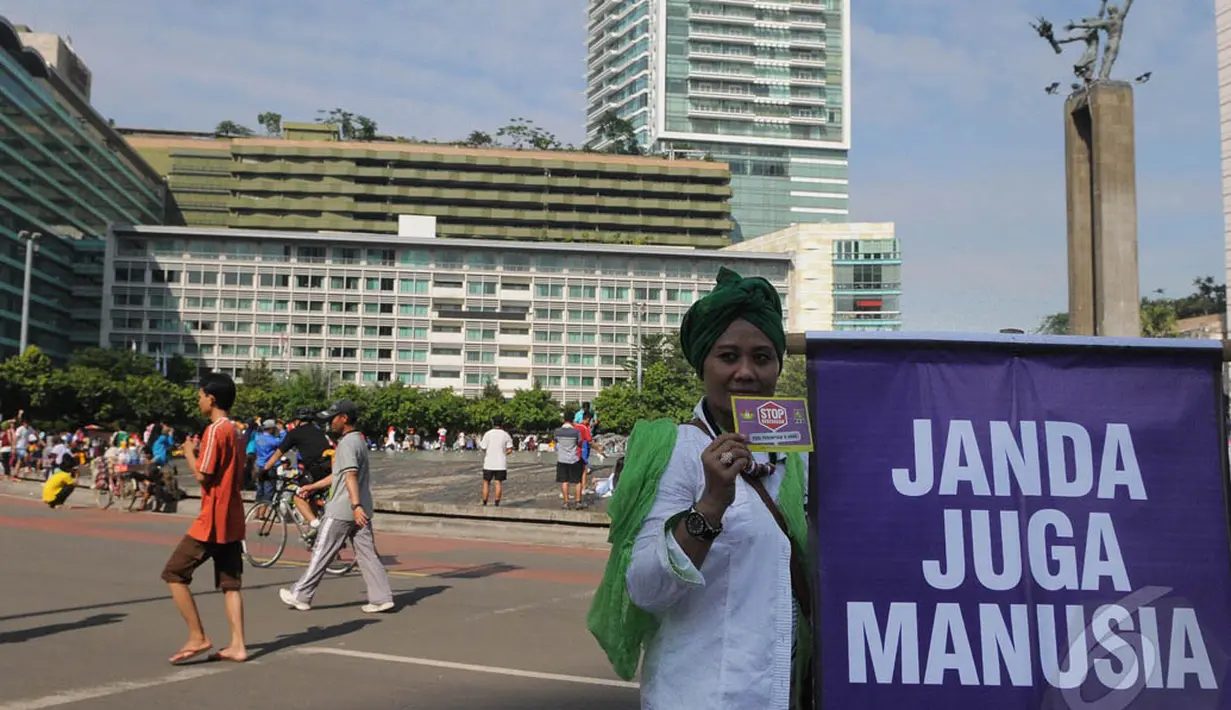 Seorang aktivis membentangkan spanduk tertulis 'janda juga manusia' saat melakukan aksi peringatan Hari Ibu di Bundaran HI, Jakarta, Minggu (21/12/2014). (Liputan6.com/Herman Zakharia)