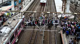 Puluhan calon penumpang melintasi rel kereta api di Stasiun Tanah Abang, Jakarta, Senin (11/7). Stasiun Tanah Abang mulai ramai di awal kerja usai libur lebaran. (Liputan6.com/Faizal Fanani)