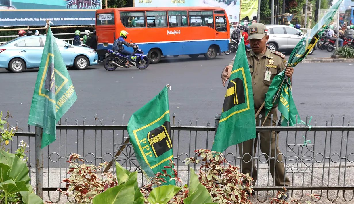 Petugas Satpol PP mencopot bendera partai politik di sepanjang pagar kawasan Pancoran, Jakarta. Selasa (18/7). Pencopotan dilakukan untuk menertibkan bendera partai politik liar yang memenuhi ruang publik di Ibukota. (Liputan6.com/Immanuel Antonius)