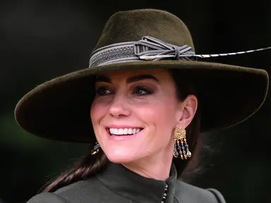 Kate Middleton, Princess of Wales dari Inggris tersenyum usai kebaktian Natal di Sandringham, Norfolk, Inggris pada 25 Desember 2022. Ibu tiga anak ini tampak bergaya dalam balutan coat hijau olive panjang yang bagian bawahnya lebar dari koleksi Alexander McQueen. (AFP/Daniel Leal)