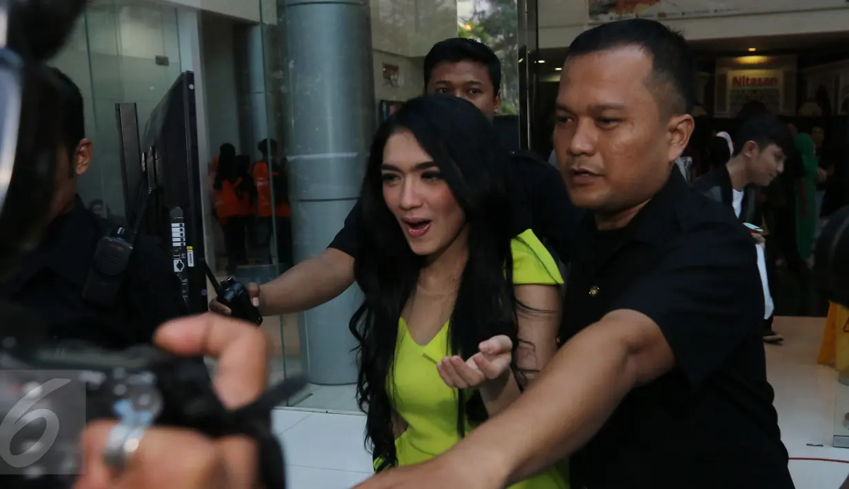 Angel Karamoy bergegas menuju mobil dengan dikawal oleh salah satu petugas, Jakarta, Rabu (30/12). Angel masih tetap bungkam saat di tanyai wartawan tentang permasalahan rumah tangganya. (Liputan6.com/Herman Zakharia)