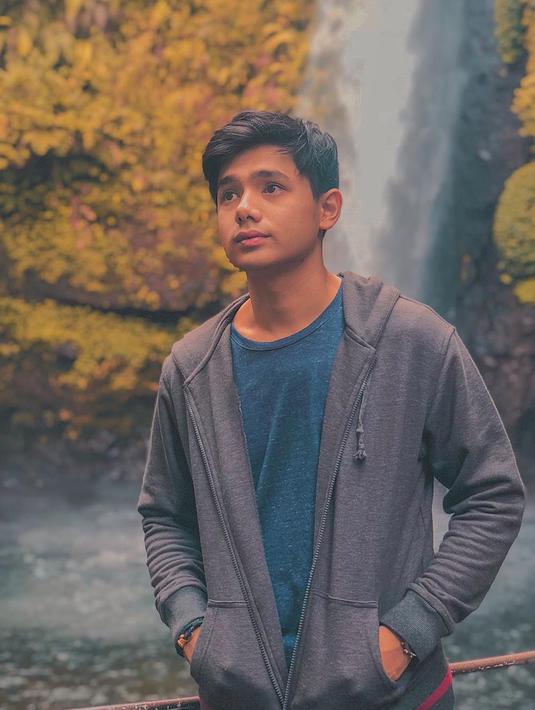 Wisata alam menjadi tempat favorit untuk melepas penat. Tak ketinggalan. Rayn Wijaya juga memilih untuk menikmati keindahan air terjun. Saat di air terjun, ia memilih gaya kasual dengan jaket yang dipadukan dengan kaus. (Liputan6.com/IG/@raynwijaya26)