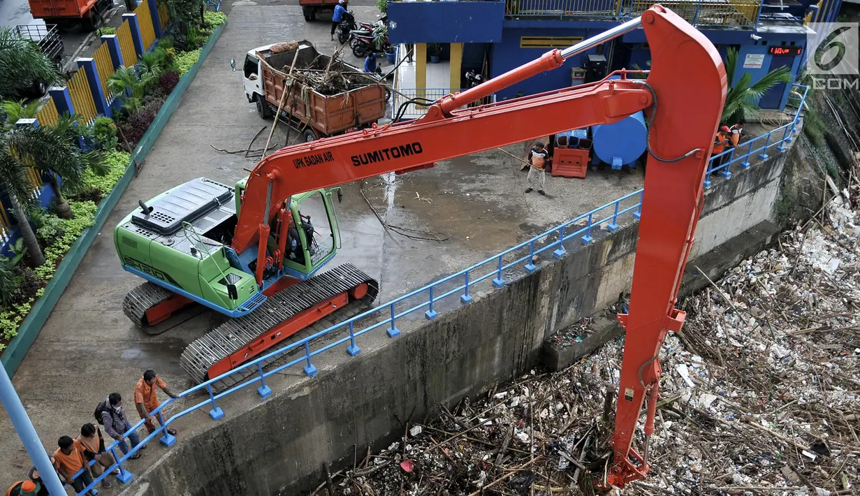 Alat berat mengangkut sampah yang memenuhi sekitar Pintu Air Manggarai, Jakarta, Minggu (8/4). Tumpukan sampah akibat arus air dari hulu meningkat. (Merdeka.com/Iqbal Nugroho)