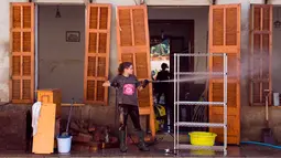 Seorang wanita membersihkan rumahnya yang terkena banjir bandang di Sant Llorenc, Mallorca, Spanyol (11/10). Banjir bandang tersebut telah menewaskan setidaknya 10 orang. (AP Photo/Francisco Ubilla)