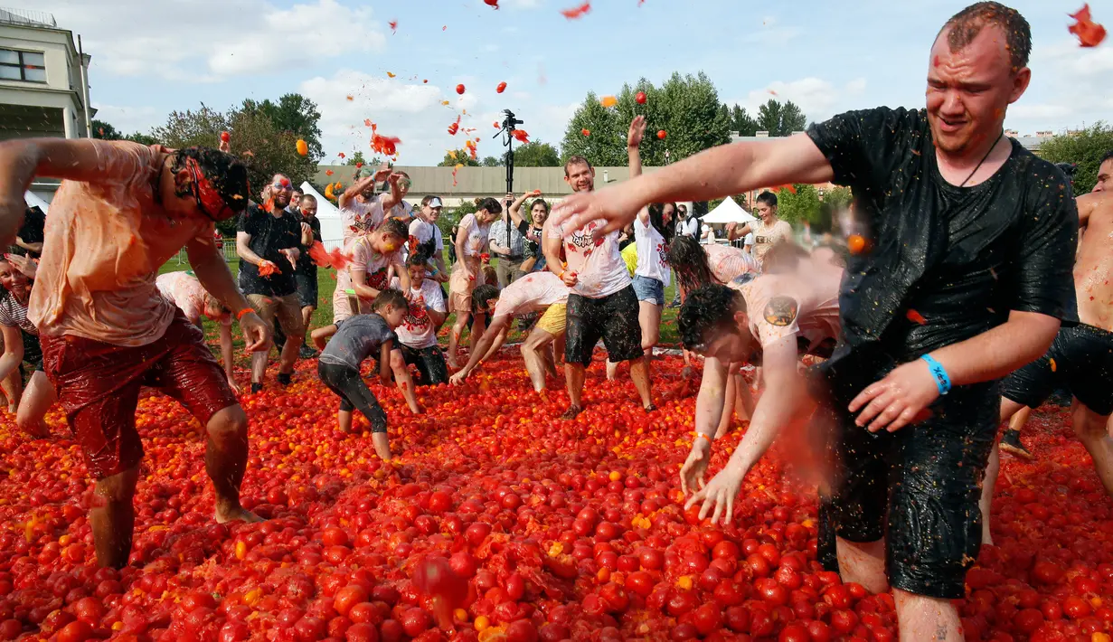 Orang-orang saling melempar tomat ketika berpartisipasi dalam festival 'Tomatina' atau perang tomat di St.Petersburg, Rusia, Minggu (18/8/2019). Tomatina atau perang tomat adalah festival Spanyol, dan tahun ini merupakan pertama kalinya dirayakan di Rusia. (AP Photo/Dmitri Lovetsky)