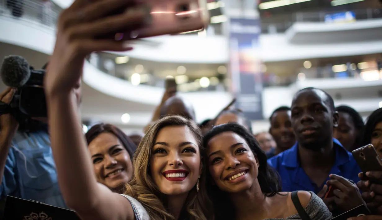 Miss Universe 2017 asal Afrika Selatan, Demi-Leigh Nel-Peters berswafoto dengan penggemarnya saat tiba di Bandara Internasional OR Tambo di Johannesburg (24/1). (AFP Photo/Gulshan Khan)