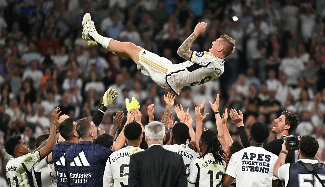 Pemain Real Madrid melemparkan Toni Kroos ke udara saat upacara perpisahan untuk sang pemain setelah laga Liga Spanyol 2023/2024 melawan Real Betis di Santiago Bernabeu, Madrid, Spanyol, Minggu (26/05/2024) dini hari WIB. Kroos memutuskan untuk pensiun dari sepak bola setelah Euro 2024 nanti. (AFP/Javier Soriano)