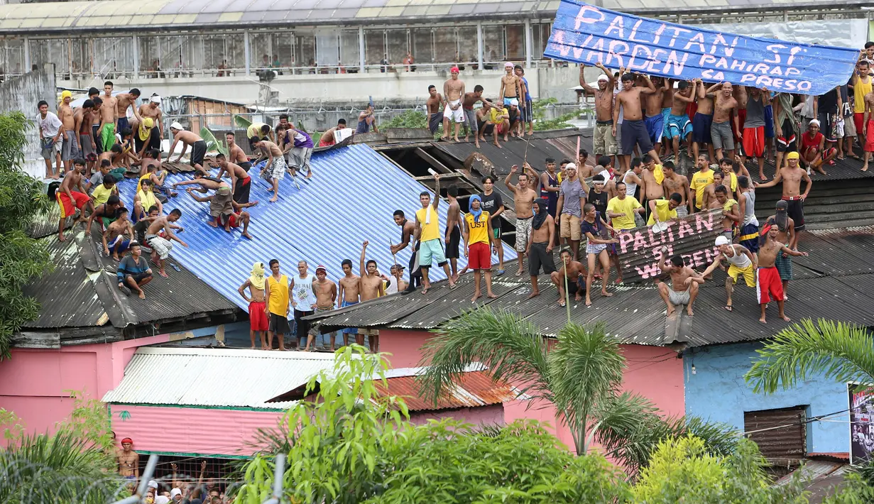 Ratusan Narapidana berkumpul di atap penjara saat unjuk rasa menuntut penggantian kepala penjara di Manila City Jail, Filipina (13/10). Para narapidana mengelar aksi nekat dengan menaiki atap penjara dan membentangkan spanduk protes. (REUTERS/Stringer)