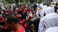 Polisi mengamankan aksi ratusan buruh dari FSMPI dan Perwakilan Daerah KSPI terlibat saling dorong dengan polisi di depan Balai Kota DKI Jakarta, Senin (29/11/2021). Buruh menuntut Gubernur DKI Jakarta Anies Baswedan membatalkan Upah Minimum Provinsi (UMP) Jakarta 2022. (Liputan6.com/Faizal Fanani)