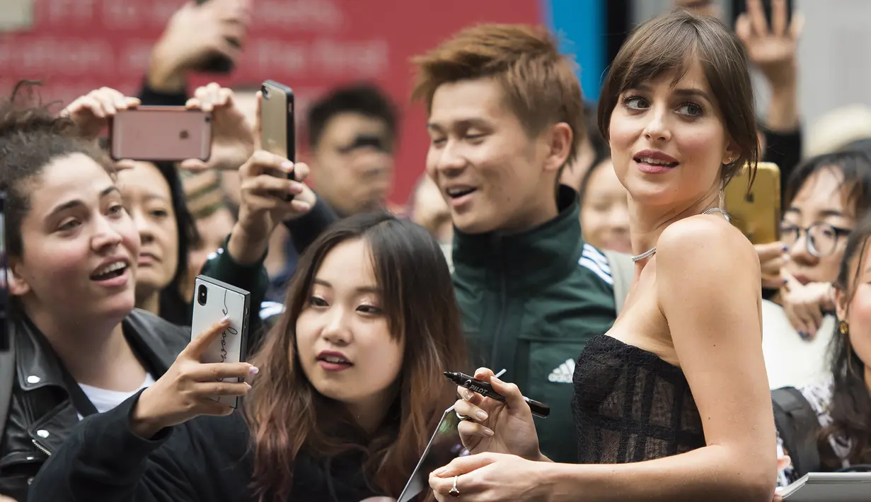 Aktris Dakota Johnson berfoto bersama penggemarnya saat menghadiri pemutaran film "The Friend" di Toronto International Film Festival di Toronto, AS (6/9/2019). Dakota Johnson tampil seksi mengenakan gaun hitam menerawang Dior. (Nathan Denette/The Canadian Press via AP)