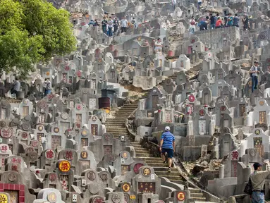 Warga mengunjungi makam keluarga dan kerabat selama festival Qingming di pemakaman di Hong Kong (5/4). Festival Qingming atau dikenal sebagai Hari Pembersihan Makam untuk menghormati orang yang dicintainya yang telah tiada. (AFP Photo/Isaac Lawrence)