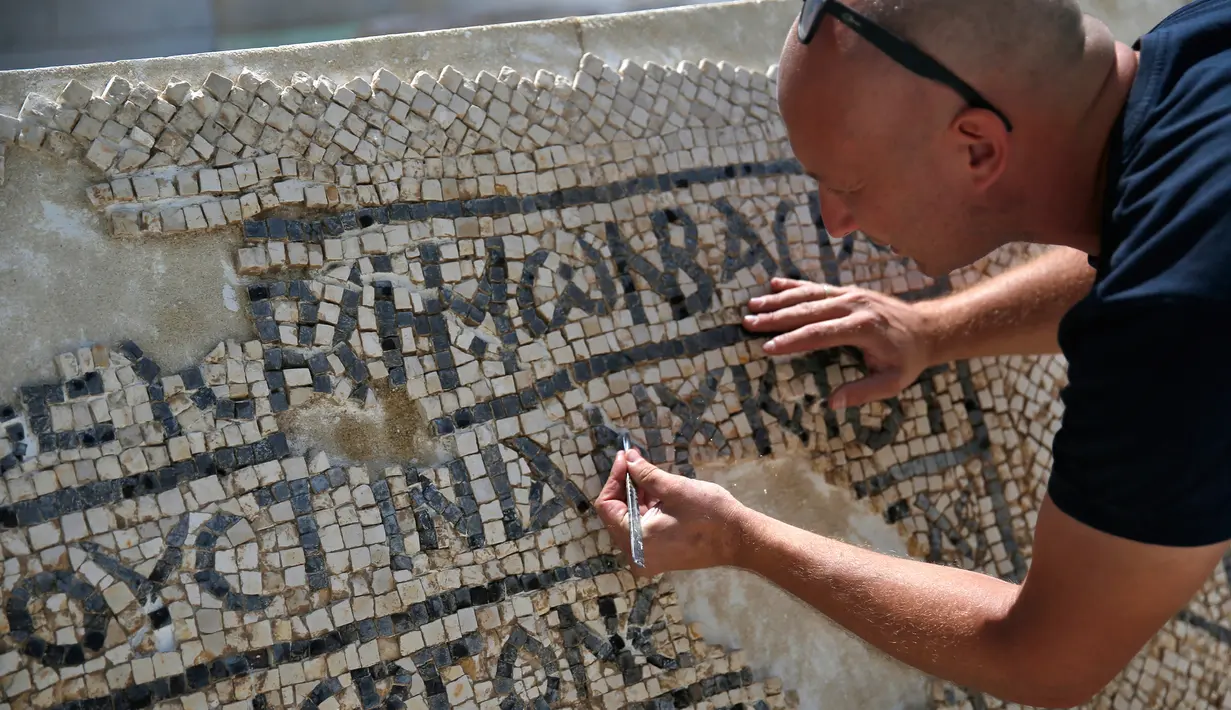 Seorang arkeolog meneliti lantai mosaik berusia 1.500 tahun di Museum Rockefeller, Yerusalem, Rabu (23/8). Ahli konservasi telah merawat mosaik yang ditemukan pada awal musim panas ini di sebuah loka karya spesialis. (AHMAD GHARABLI/AFP)
