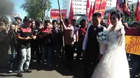 Pasangan calon pengantin menggelar foto pra-nikah berlatar unjuk rasa peringatan Harkitnas di depan Kantor DPRD Makassar, Sulsel, Jumat (20/5/2016). (Liputan6.com/Eka Hakim)‎