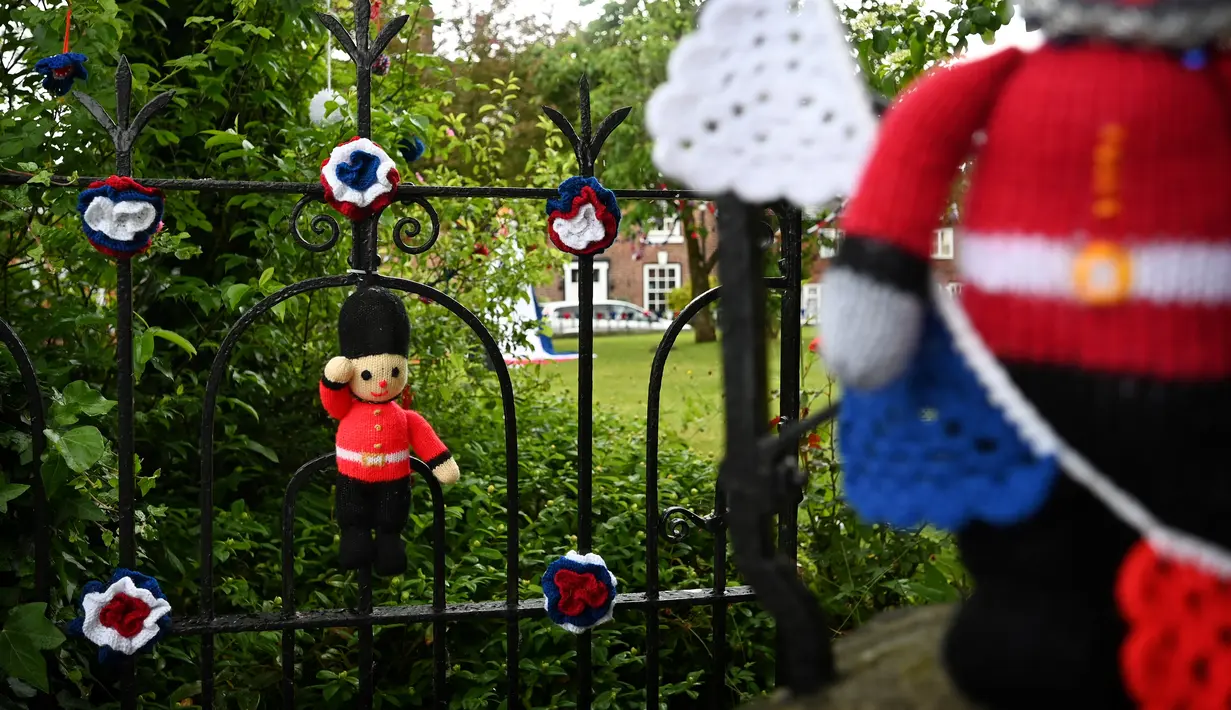 Boneka penjaga Inggris rajutan terpasang di gerbang Gereja St Luke di Kapel Holmes, barat laut Inggris, pada 30 Mei 2022. Sebuah kelompok masyarakat lokal, The Holmes Chapel Community Yarn Bombers telah memenuhi desa dengan barang-barang rajutan patriotik untuk merayakan Platinum Jubilee Ratu. (Paulus ELLIS / AFP)