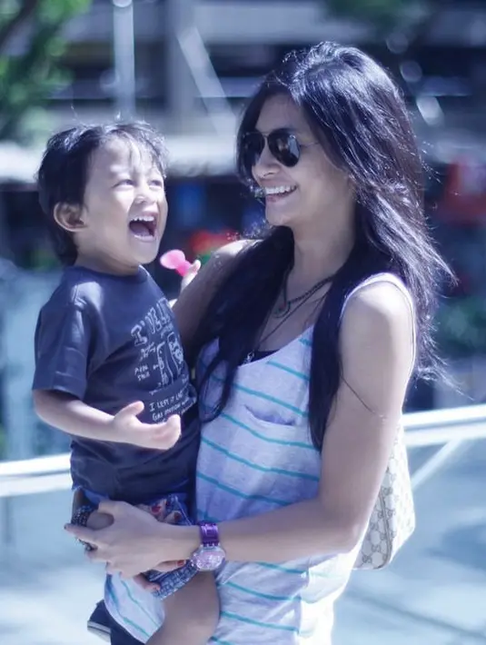 Menggendong si kecil, Raihaanun tampil jadi mamah muda mengenakan atasan tanpa lengan bergaris dan kacamata hitamnya. (@raihaanun)