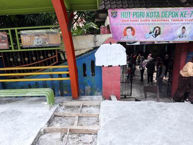 Sejumlah siswa berjalan keluar melintasi jalan darurat yang dibuat pihak sekolah di SDN Pondok Cina 1, Depok, Jawa Barat, Rabu (9/11/2022). Pembangunan trotoar Jalan Margonda Raya yang tidak membuat jalan darurat untuk siswa tersebut menghalangi pintu masuk SDN Pondok Cina 1 serta membahayakan siswa. (Liputan6.com/Herman Zakharia)