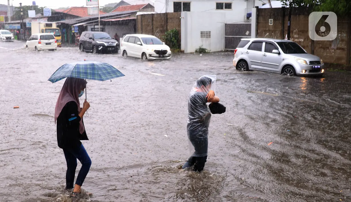 Warga melintasi banjir di jalan Bayangkara Pusdiklat, Kota Tangerang Selatan, Banten, Selasa (2/11/2021). BMKG mengeluarkan peringatan potensi cuaca ekstrem di wilayah Jakarta, Bogor, Depok, Tangerang, dan Bekasi (Jabodetabek). (Liputan6.com/Angga Yuniar)