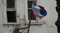 Seorang pria mengambil bendera nasional Rusia dari tiang di luar Kedutaan Besar Rusia di London, Rabu (14/3). Inggris diketahui mengusir 23 diplomat Rusia menyikapi kasus mantan agen ganda Rusia yang diduga diracun zat saraf langka. (AP/Alastair Grant)