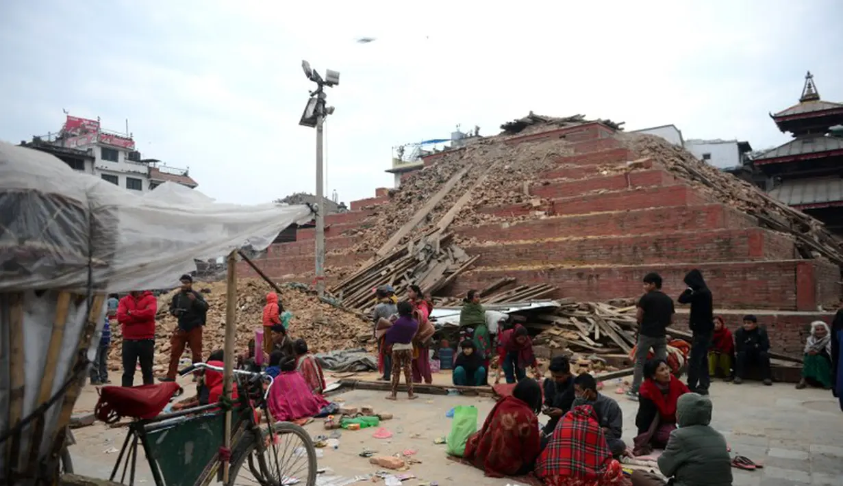 Sejumlah warga Nepal terlihat beristirahat di sekitar Kathmandu Durbar Square yang rusak parah, Minggu (26/4/2015). Gempa berkekuatan 7,8 Skala Richter itu dikabarkan telah menghancurkan ribuan rumah dan bangunan bersejarah (AFP Photo/Prakash Mathema)