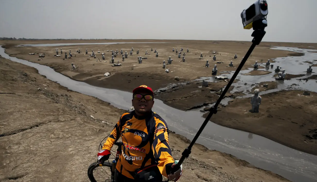 Pengendara sepeda berselfie dengan latar belakang area lumpur Lapindo di Sidoarjo, Jawa Timur, 11 Oktober 2015. Beberapa tahun silam, Porong didera bencana, namun kini kawasan tersebut malah jadi objek wisata yang tak biasa. (REUTERS/Beawiharta)