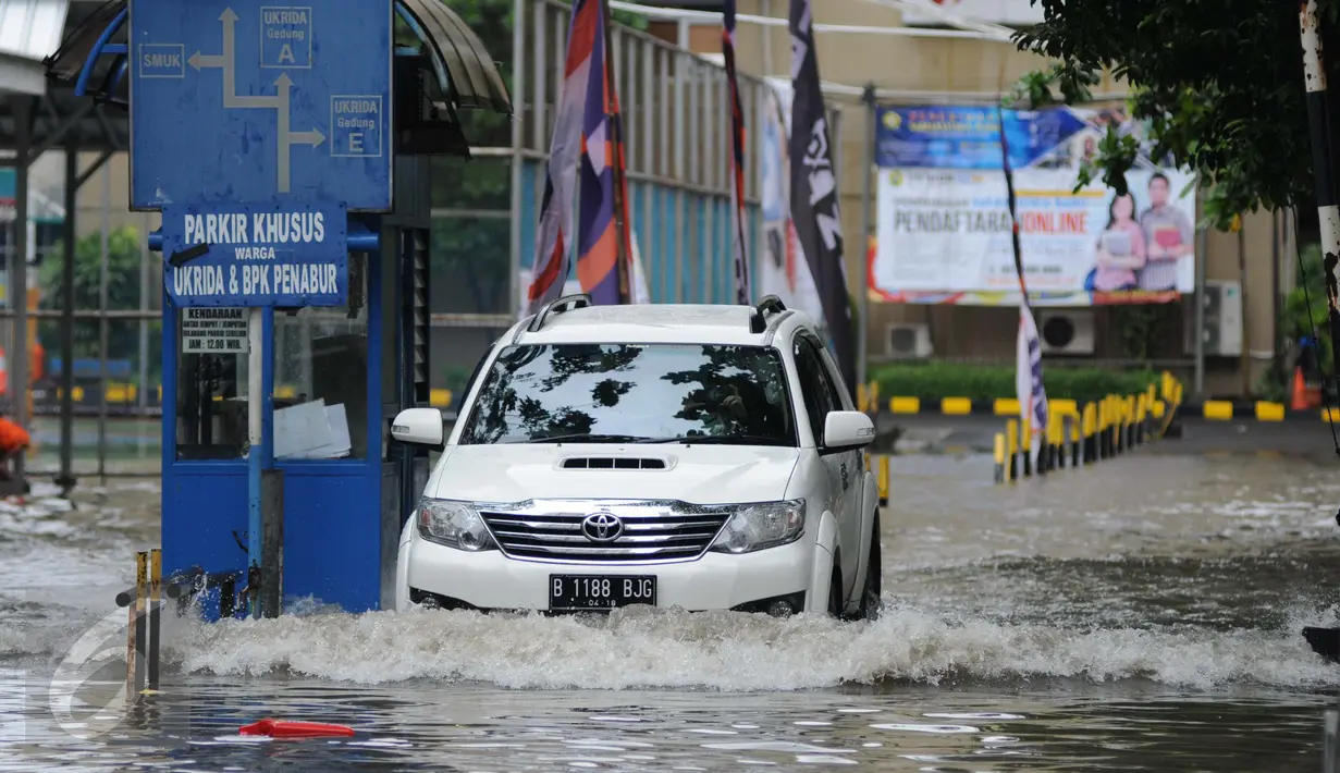 Sebuah mobil menerobos genangan air di depan kampus UKRIDA, Jakarta, Selasa (21/1). Hujan deras sejak malam tadi, membuat sejumlah wilayah Jakarta tergenang air banjir. (Liputan6.com/Gempur M Surya)