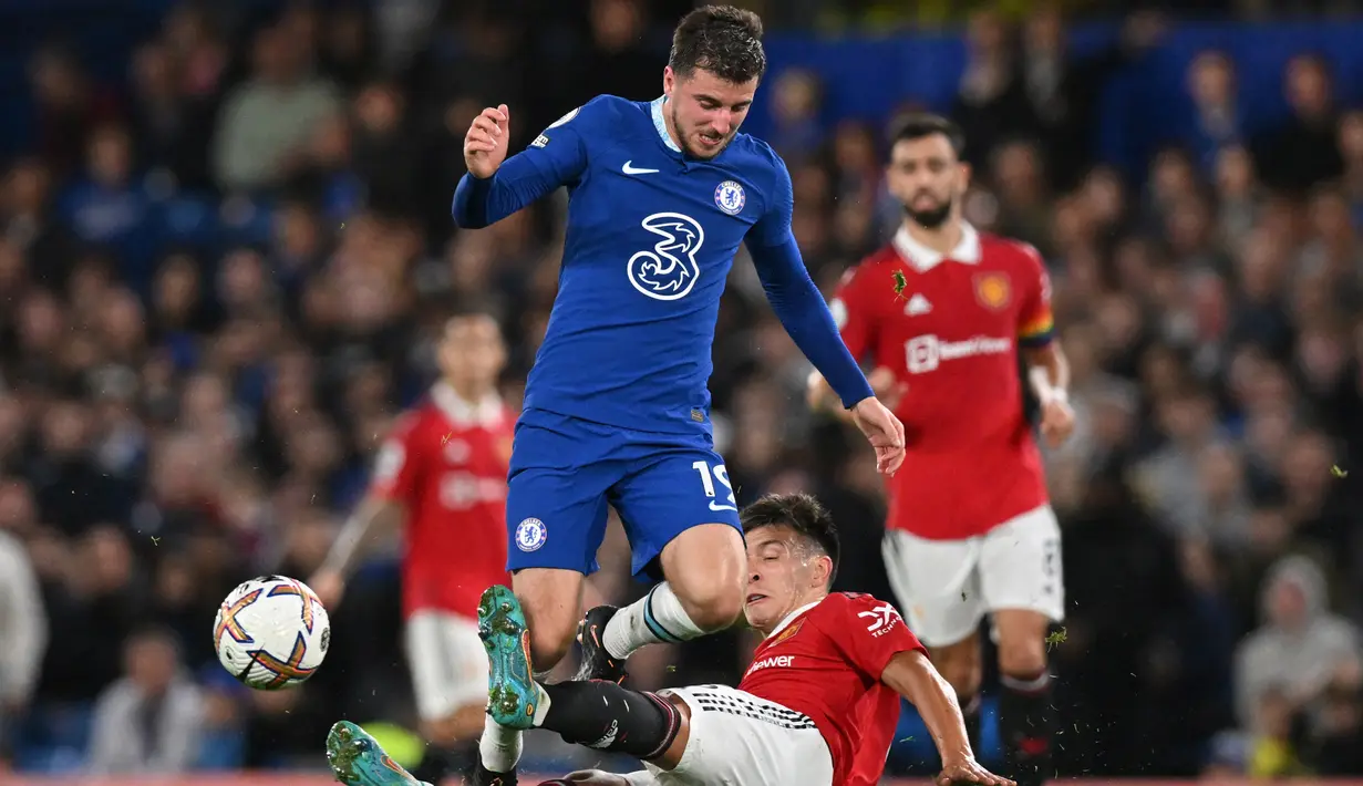 Pemain MU, Lisandro Martinez (tengah), berusaha menghalau laju pemain Chelsea, Mason Mount, dalam pertandingan Liga Inggris 2022/2023 antara Chelsea dan Manchester United yang berlangsung di Stamford Bridge, Sabtu (22/10/2022). (AFP/Adrian Dennis)