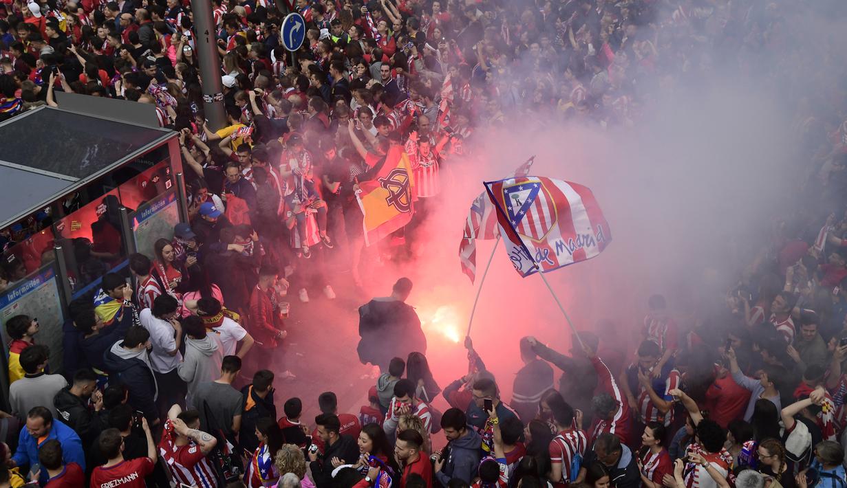 Warga Madrid menyalakan flare saat menyambut konvoi Atletico Madrid merayakan gelar Liga Europa di Madrid, Jumat (18/5/2018). Kota Madrid menjadi merah saat perayaan gelar juara Atletico. (AFP/Javier Soriano)