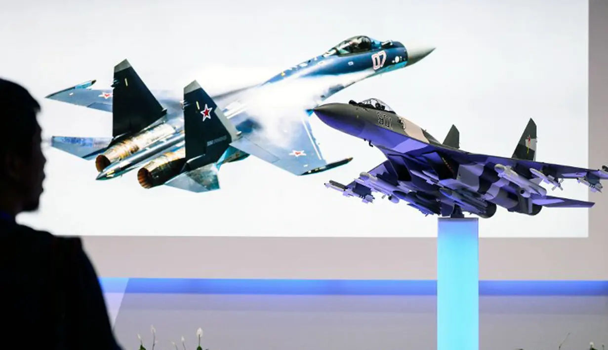 Salah satu pengunjung memerhatikan replika pesawat jet tempur buatan Rusia, Sukhoi SU-35, di pameran dirgantara Farnborough di Hampshire, Inggris, (14/7/2014). (AFP PHOTO/Leon Neal)