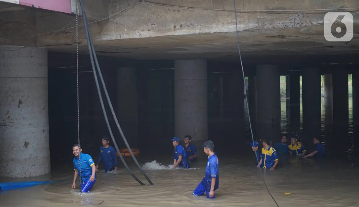 Petugas memasang pompa penyedot air di banjir yang menggenangi underpass Kemayoran, Jakarta, Senin (3/2/2020). Curah hujan tinggi menyebabkan banjir yang menggenangi kawasan tersebut lama surut sehingga menutup arus lalu lintas. (Liputan6.com/Immanuel Antonius)