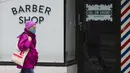 Seorang wanita yang mengenakan masker berjalan melewati tempat pangkas rambut yang tutup di Toronto, Kanada, 23 November 2020. Kanada melaporkan 5.119 kasus baru COVID-19 dan tambahan 49 kematian pada 23 November 2020 malam waktu setempat. (Xinhua/Zou Zheng)
