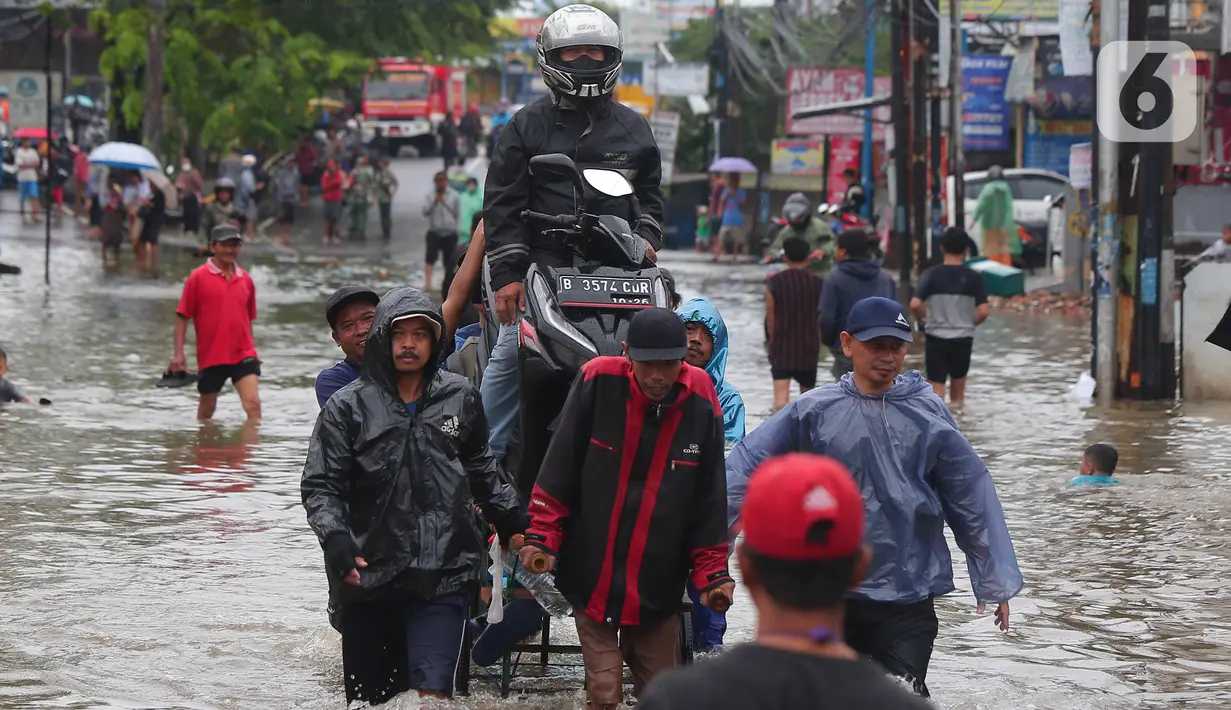 Pengendara bersama sepeda motornya berada di atas gerobak yang didorong pengojek gerobak saat melintasi banjir yang merendam jalan KH Hasyim Ashari, Kota Tangerang, Banten, Sabtu (16/7/2022). Warga sekitar membantu para pengendara yang melintas agar tidak terkena banjir dengan menawarkan jasa gerobak. (Liputan6.com/Angga Yuniar)