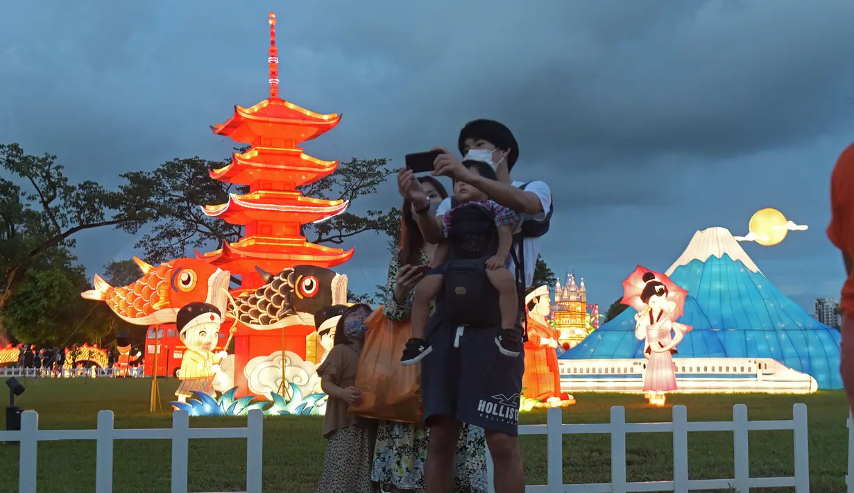 Orang-orang berswafoto di depan beraneka instalasi cahaya di "Festival Cahaya" yang diadakan di Jurong Lake Gardens, Singapura, pada 20 Desember 2020. "Festival Cahaya" berlangsung dari 18 Desember 2020 hingga 3 Januari 2021. (Xinhua/Then Chih Wey)