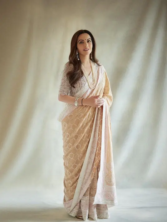 Nita Ambani dibalut sari bernuansa nude yang lembut. Sari ini mungkin terlihat sederhana, namun detail bahan, aksen, dan bordir yang dihadirkan sempurna dan mempermanis penampilan Nita secara keseluruhan di sini. [Foto: Instagram/rohanshrestha]