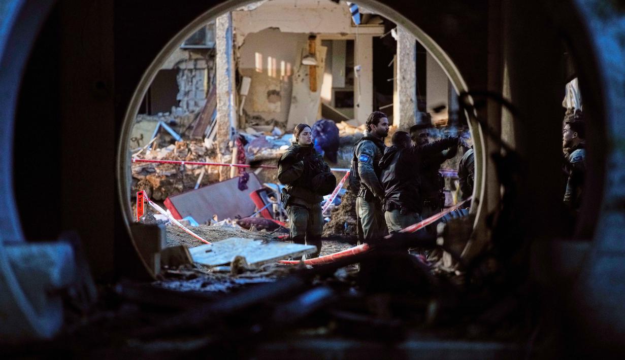 Pasukan keamanan Israel memeriksa bangunan tempat tinggal yang rusak akibat serangan rudal Iran di Arad, Israel Selatan, Minggu, 22 Maret 2026. Serangan rudal Iran menghantam kota Arad, Israel Selatan, pada Sabtu 21 Maret 2026 malam waktu setempat. (AP Photo/Ohad Zwigenberg)