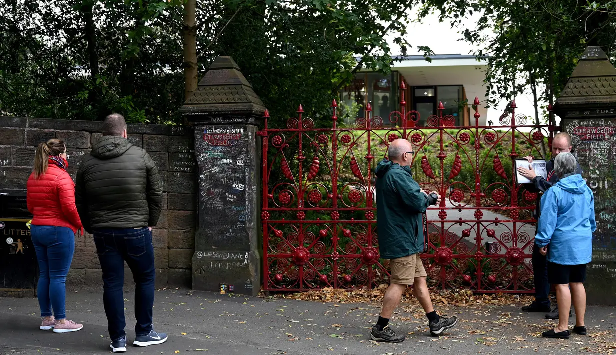 Pengunjung berdiri di depan gerbang  Strawberry Fields yang baru dibuka untuk umum di Liverpool, Rabu (18/9/2019). Strawberry Field menjadi salah satu tempat ikonis ketika John Lennon menulis lagu The Beatles “Strawberry Fields Forever” dalam album Sgt.pepper Lonely Hearts Club Band (Paul ELLIS/AFP)