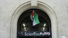 Foto yang diambil pada 26 April 2024 ini menunjukkan bendera Palestina yang digantung di pintu masuk gedung Sciences Po Paris saat pendudukan oleh para siswa yang mendukung Palestina, di Paris. (Dimitar DILKOFF/AFP)