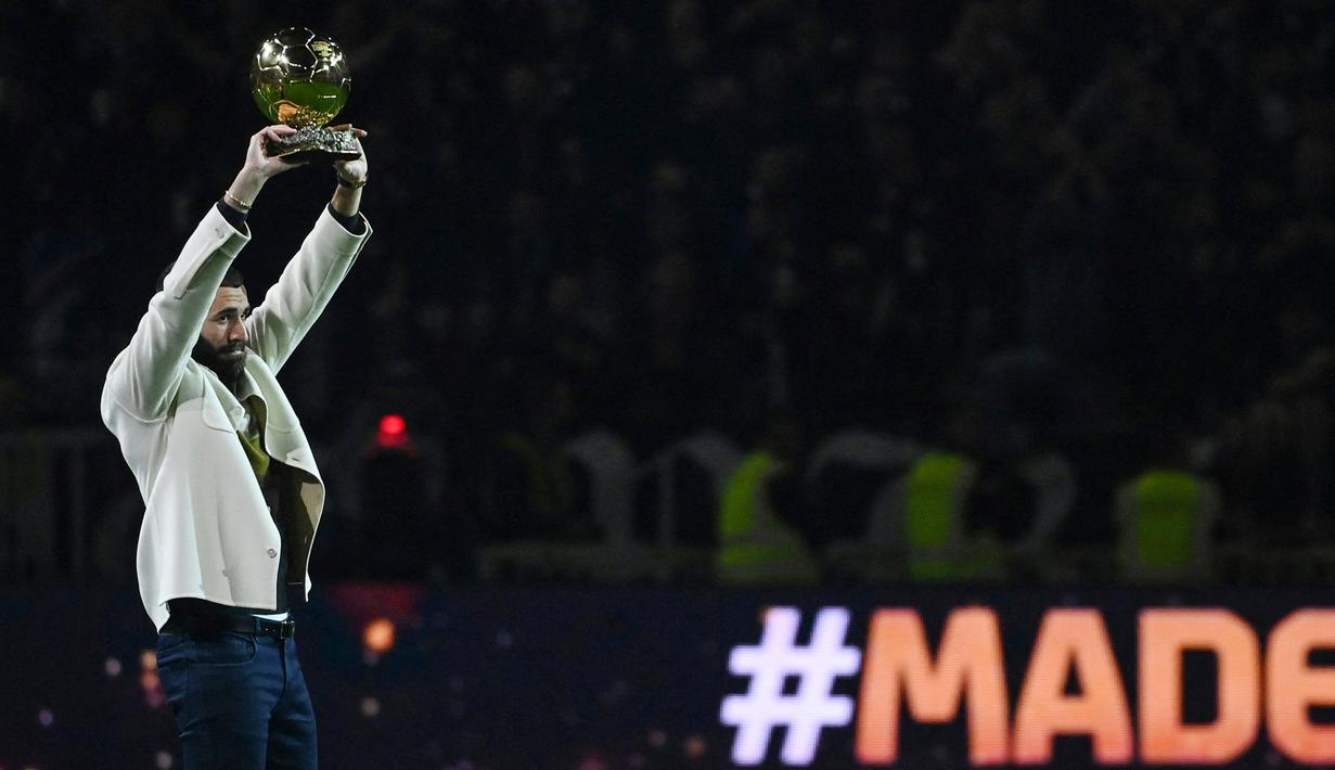 Pemain Real Madrid Karim Benzema berpose di lapangan dengan trofi Ballon d'Or miliknya pada paruh waktu pertandingan sepak bola L1 Prancis antara Olympique Lyonnais (OL) dan OGC Nice di Stadion Groupama, Decines-Charpieu, Prancis, 11 November 2022. Karim Benzema memutuskan untuk hengkang ke Real Madrid pada 2009. (OLIVIER CHASSIGNOLE/AFP)
