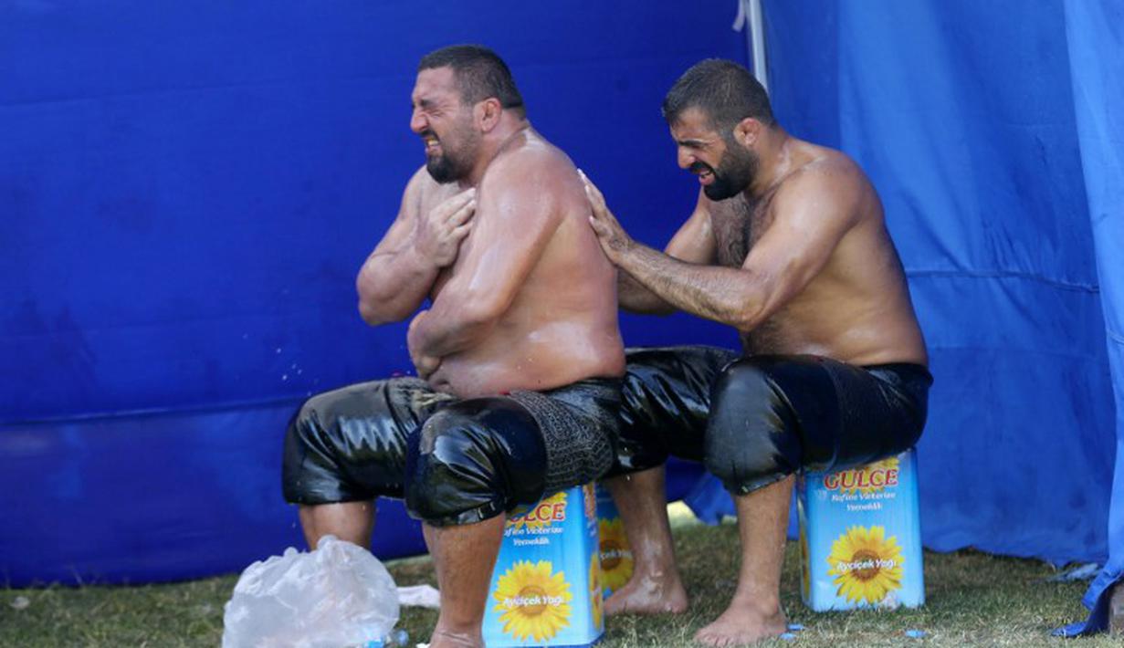Kerjasama antar peserta untuk mengoleskan oli ke tubuh peserta yang lain. (AFP Photo/Adem Altan)