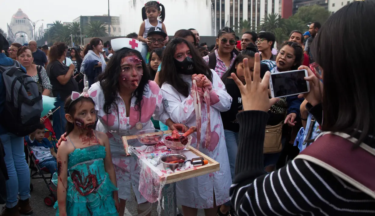 Sebuah keluarga berpose selama Zombie Walk di Mexico City, Minggu (11/11). Ratusan orang dengan penampilan yang seram serta mengenakan pakaian compang-camping berkumpul di pusat bersejarah ibu kota Meksiko dalam acara tahunan tersebut. (AP/Claudio Cruz)