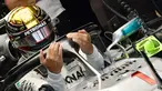 Pembalap Mercedes, Lewis Hamilton memasuki mobilnya saat sesi latihan pertama jelang GP F1 Abu Dhabi di Sirkuit Yas Marina, Jumat (23/11). Hamilton tampil berbeda dengan nomor balap yang melekat pada mobilnya. (GIUSEPPE CACACE/AFP)
